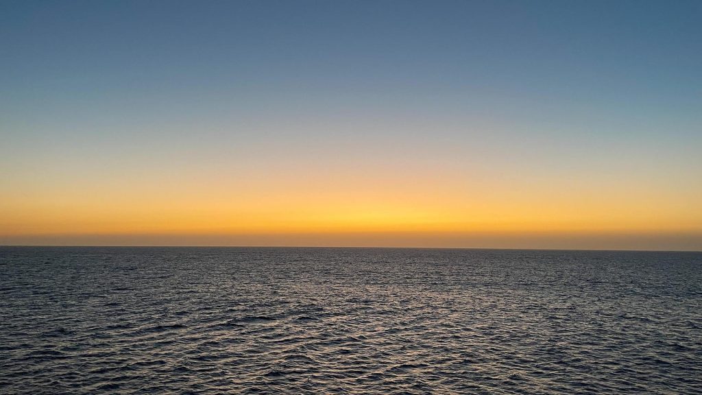 A calm horizon at sunset, with warm light reflecting on gentle waves